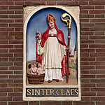 Gevelsteen met Sint Nicolaas en de drie jongetjes in een pekelvat, hoek Dam/Damrak